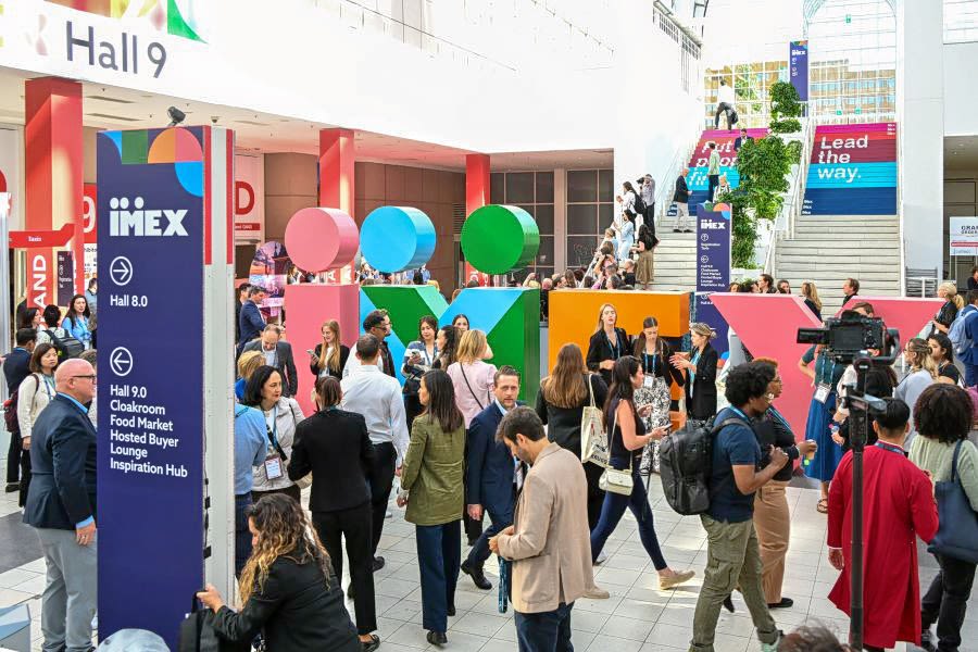 People walking in front of IMEX letters