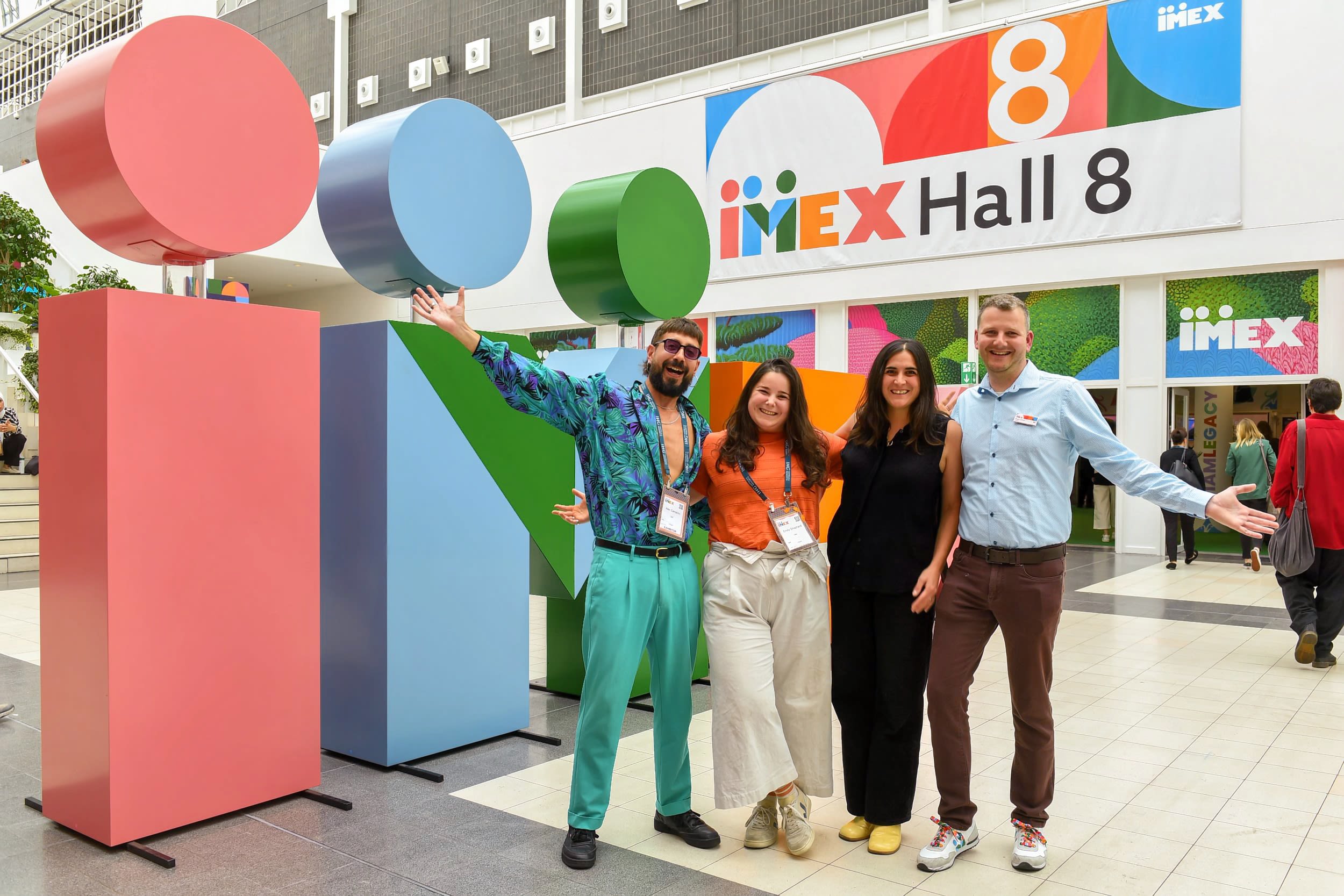Group of people posing in front of giant IMEX letters