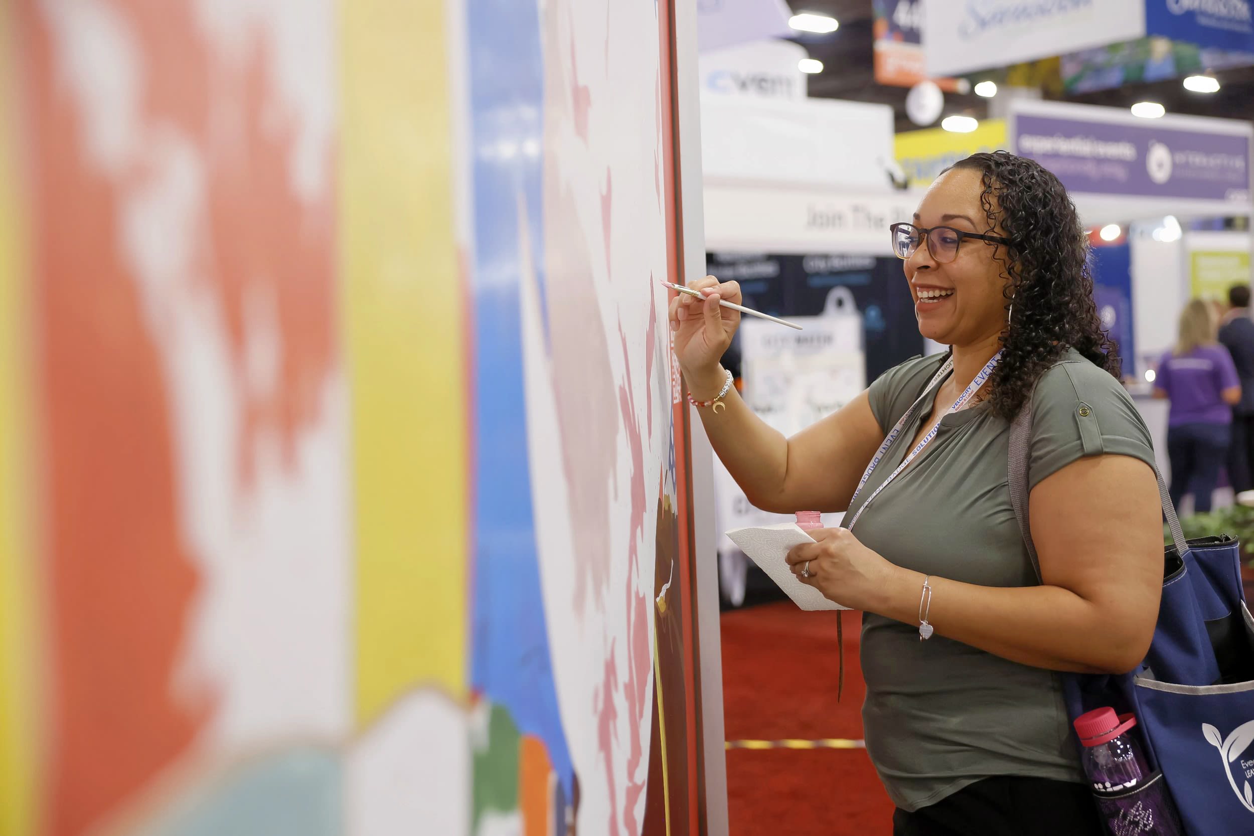 Female smiling and painting a wall to create a mural 